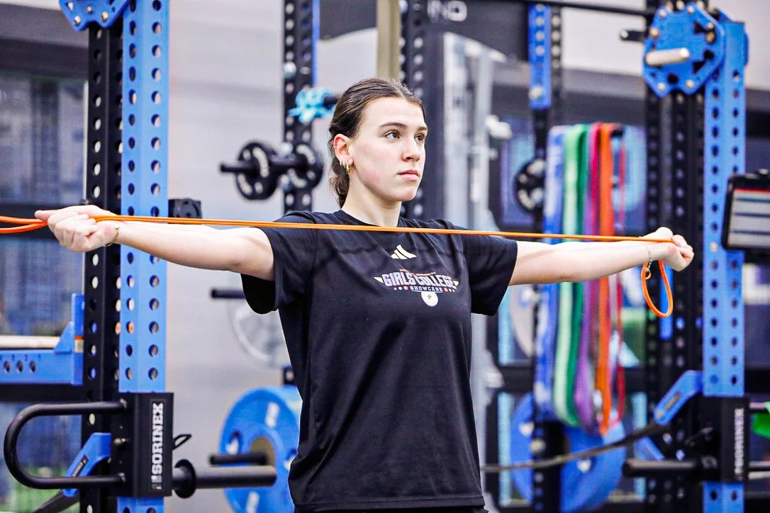Athlete doing band work in front of the power racks at Grind